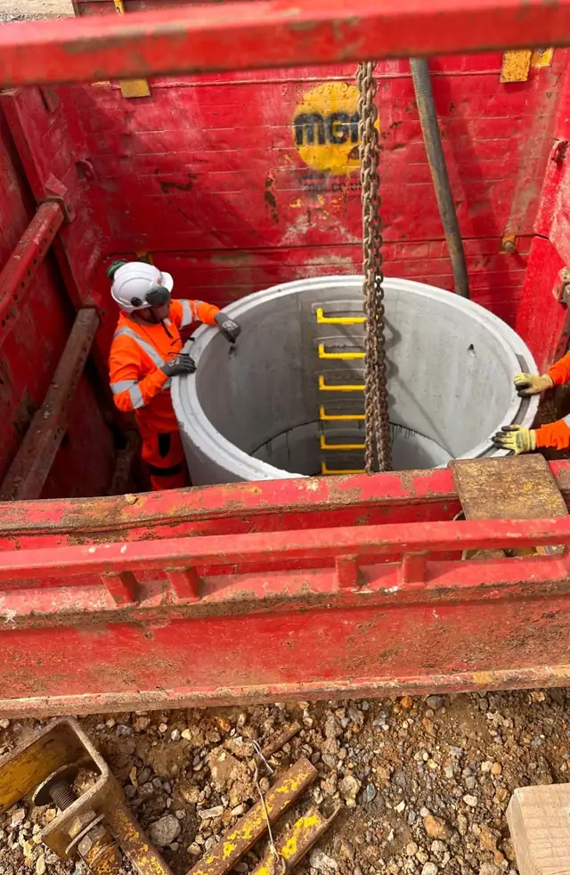 Operatives installing a concrete manhole ring in a deep excavation at Alderney Water Treatment Works